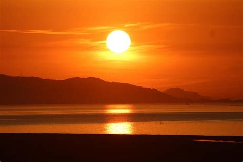 日落时分火红的太阳照射在平静的水面上自然风景素材设计