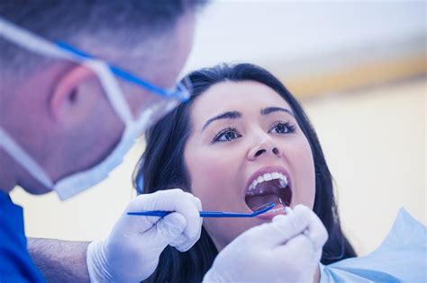 检查病人的口腔的牙科医生图片-牙医在牙科医生的椅子上检查病人的口腔素材-高清图片-摄影照片-寻图免费打包下载