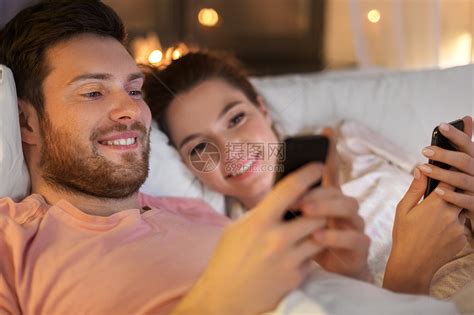 快乐的夫妇晚上床上用智能手机高清图片下载-正版图片300056768-摄图网