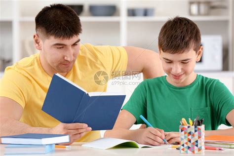 沙发上父亲辅导孩子写作业高清图片下载-正版图片500957527-摄图网