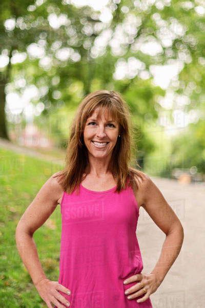 Portrait Of Happy Fit Mature Woman Standing With Hands On Hips At Park ...