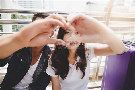 肖像旅行者夫妇英俊的男朋友和美丽的女朋友正在用他们的手和指制作一个心形来象征爱他们一起度蜜月高清图片下载-正版图片502536186-摄图网