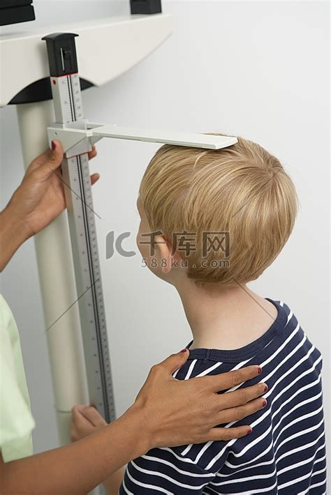 年轻女护士测量男孩的身高头发女人高清摄影大图-千库网