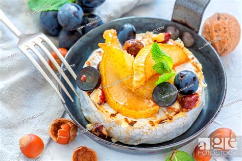 Grilled camembert with pears and black grapes in a cast iron skillet ...