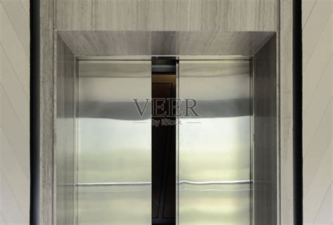 微微打开的电梯门。电梯门套由金属不锈钢制成，安装在商务办公楼门口、入口大厅或走廊的电梯上。照片摄影图片_ID:309555055-Veer图库
