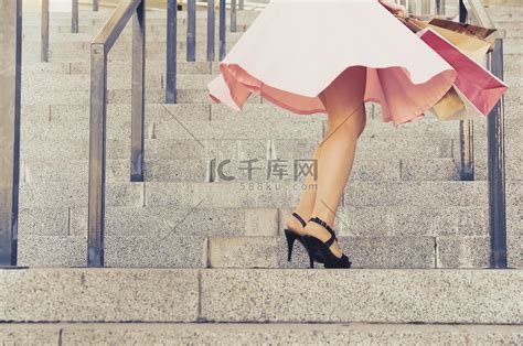 一个穿裙子的女孩拿着纸包在楼梯上旋转高清摄影大图-千库网