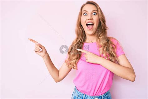 带着金发的年轻caucasian女子用手指对着一边庆祝疯狂和惊异的成功高清图片下载-正版图片503680885-摄图网