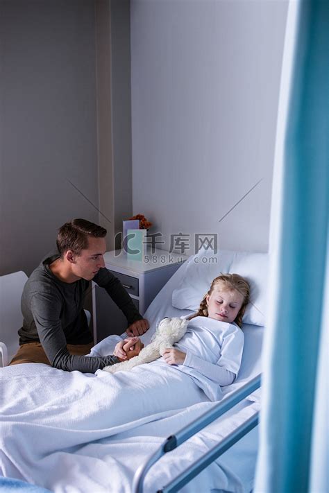 坐在躺在病床上的女儿旁边的父亲高清摄影大图-千库网