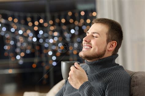 快乐男人晚上喝咖啡坐在家里客厅的沙发上高清图片下载-正版图片304507007-摄图网