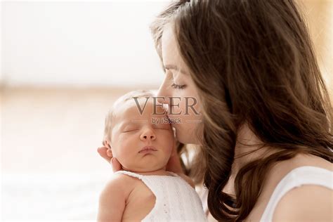 刚出生的婴儿在母亲的怀里躺在床上。母亲节明信片。保护的一天。世界上幸福的一天。微笑的孩子和女人。照片摄影图片_ID:420692485-Veer图库