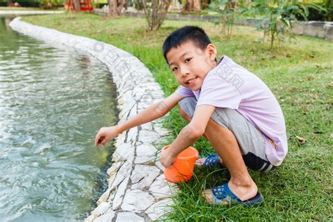 年轻的泰国男孩喂养鱼池塘图片-包图网