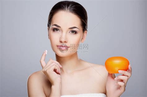完美裸妆的女孩的美丽肖像美丽的女孩拿着橙色奶油看着相机和微笑美容高清图片下载-正版图片503042821-摄图网