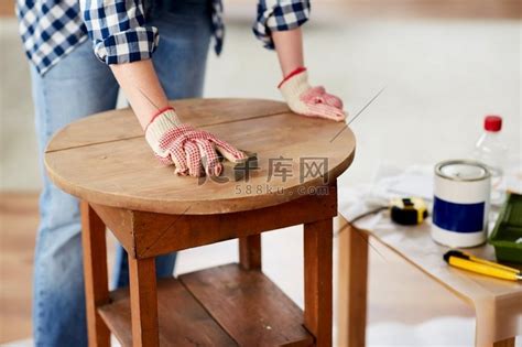 家具翻新、DIY 和家居改善概念 — 女人用海绵打磨旧木桌的特写。高清摄影大图-千库网