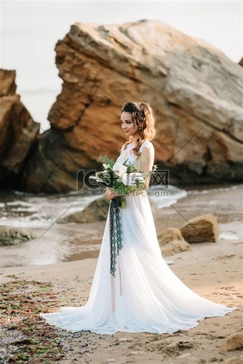 在夕阳的黑海岸边，新娘带着婚礼花束高清摄影大图-千库网