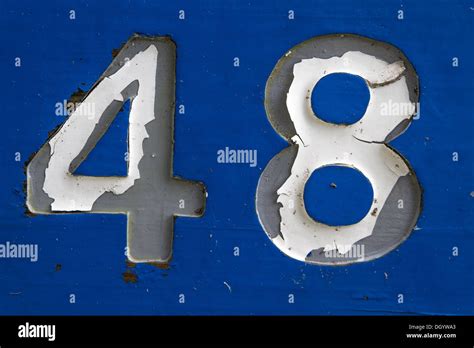 Gold number 48 (number forty-eight) with perforated black metal background and gold rings around ...