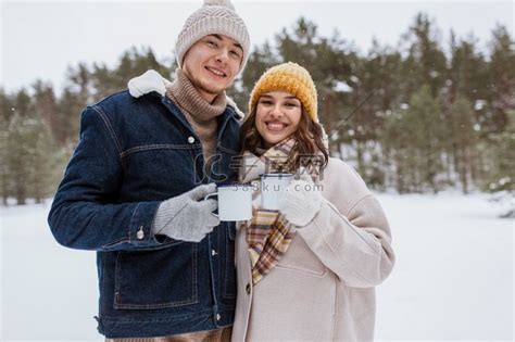 人、季节、爱情、饮料和休闲概念-幸福的情侣在白雪皑皑的冬季公园喝茶。高清摄影大图-千库网