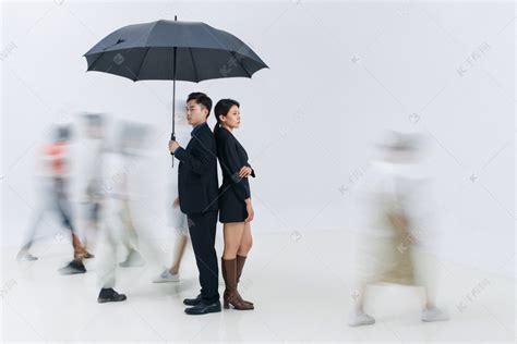 拿着雨伞的商务男女站在人群中高清摄影大图-千库网