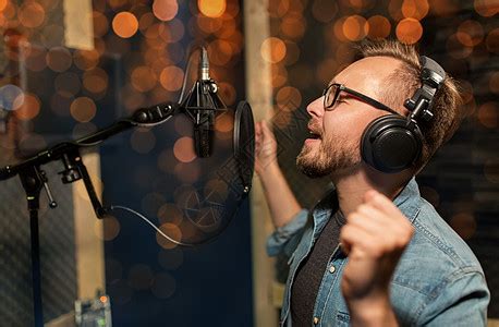 音乐,表演业务,人声音男歌手戴着耳机麦克风录音室唱歌,灯光音符带耳机的男人录音棚唱歌高清图片下载-正版图片300120000-摄图网