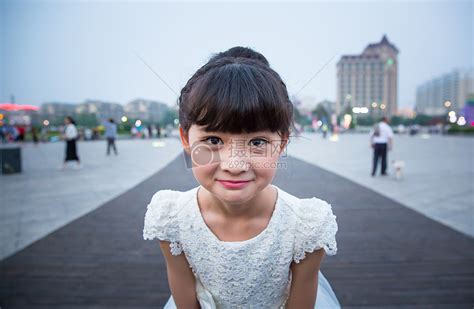 傍晚小姑娘穿着白裙站在广场上露出特殊的表情高清图片下载-正版图片500129151-摄图网