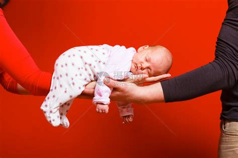 一个月大的女婴睡在父母怀抱红色背景的舒适中高清图片下载-正版图片304029444-摄图网