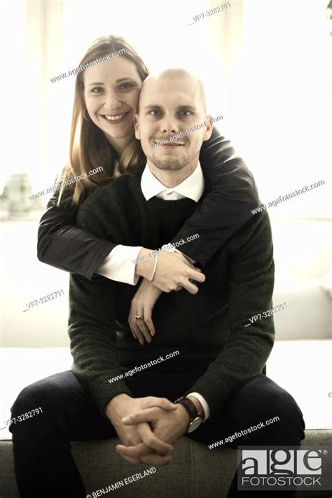 mid adult couple at home, wife embracing husband from behind, looking ...