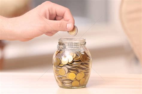 男人把硬币放在桌子上的玻璃罐里储蓄概念高清图片下载-正版图片505263737-摄图网