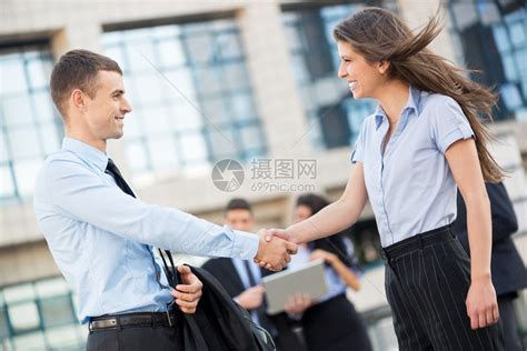 年轻的女商人和商人在公司面前握手高清图片下载-正版图片504866263-摄图网