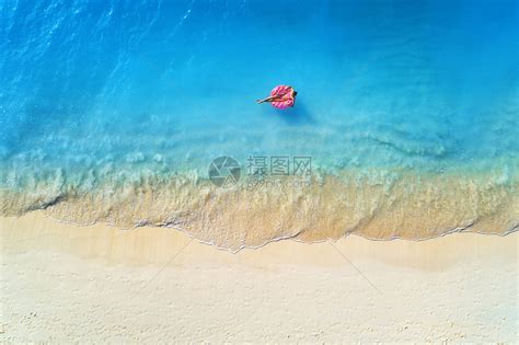 鸟瞰个轻的女人游泳与甜甜圈游泳环清澈的蓝色海洋与波浪日落夏天热带航空景观与女孩,蔚蓝的水,沙滩的风景旅高清图片下载-正版图片300877451-摄图网