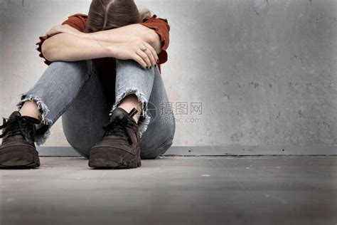 绝望虐待成人年轻女子哭泣坐在空荡的墙边孤独悲伤和沮丧的女孩低着头高清图片下载-正版图片308004942-摄图网