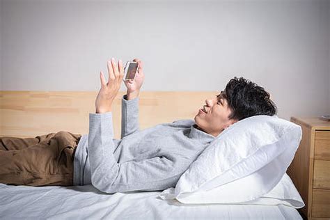 深夜男人躺在床上看手机图片下载 - 觅知网