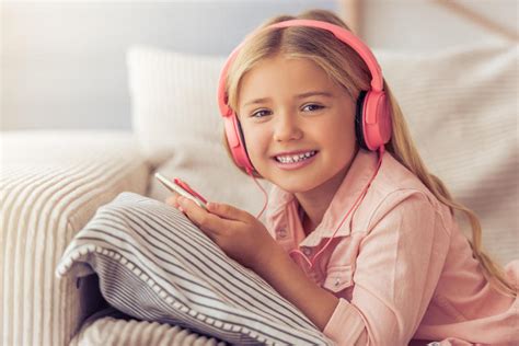 小女孩趴着玩手机带耳机听歌头戴耳机微笑的小女孩图片下载 - 觅知网