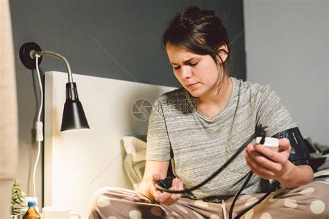 高血压的主题是高血压疾病22岁的年轻白种女人晚上在卧室的床上使用自动眼压计检高清图片下载-正版图片506461292-摄图网