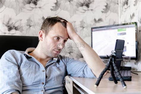 年轻无聊的男自由职业男子在家中坐在家里时用智能高清图片下载-正版图片503752520-摄图网