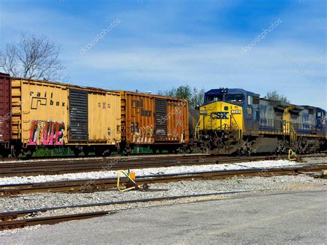 Una fila de vagones de carga con una locomotora diesel # 7348 CSX ...