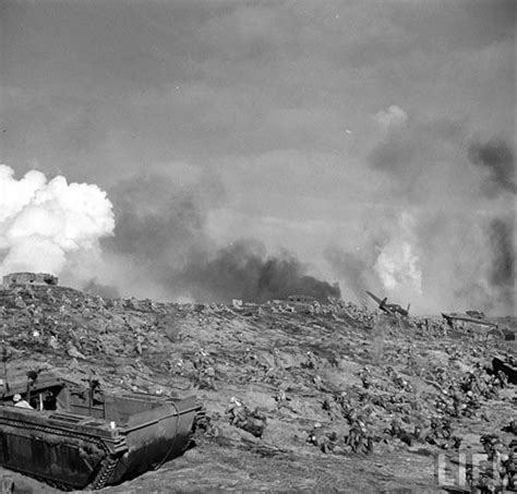1945年2月-3月间，硫磺岛战役，一名美海军陆战队员躲避爆炸的冲击波，远处的山就是硫磺岛的制高点-折钵山，整座山都被日军改造成一个大碉堡。