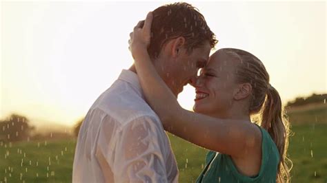 近距离观察:在一个风景如画的晚上，轻松的年轻夫妇在雨中亲吻。视频素材_ID:VCG42N957879212-VCG.COM