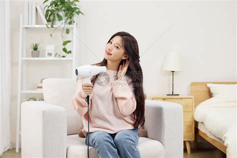 冬日居家女性使用吹风机吹头发高清图片下载-正版图片507513830-摄图网