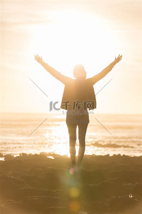 自由的女人在日落时在海滩上享受自由。高清摄影大图-千库网