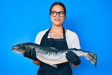 年轻漂亮的亚洲女孩鱼贩卖新鲜的生鲑鱼高清图片下载-正版图片504373184-摄图网