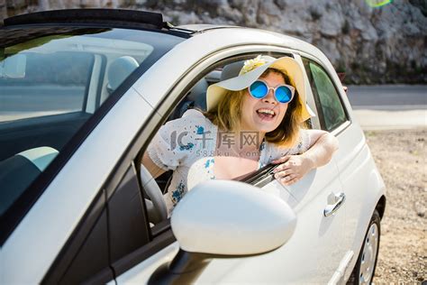 一个女人开车进入一个停车场，把车票插进车库的栅栏里,,,摄影,汇图网www.huitu.com