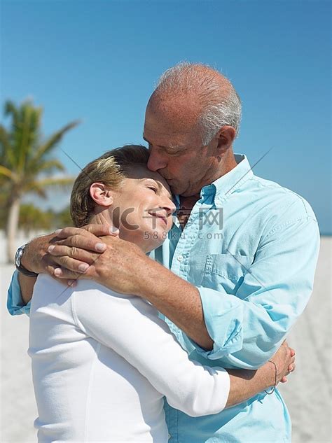 在热带海滩上拥抱的老夫妇亲吻人物特写老年人高清摄影大图-千库网