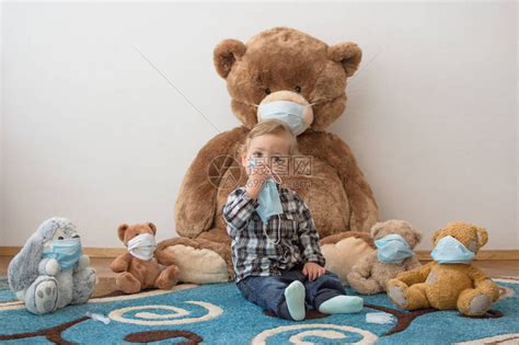 孩子戴着防的医用口罩和生病的泰迪熊玩耍高清图片下载-正版图片506449942-摄图网