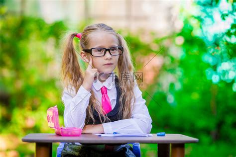 聪明的小女生坐在办公桌前，带着笔记和铅笔在户外。高清摄影大图-千库网