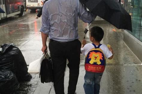 一张父亲为儿子撑伞的照片，画面让人震撼又让人深思