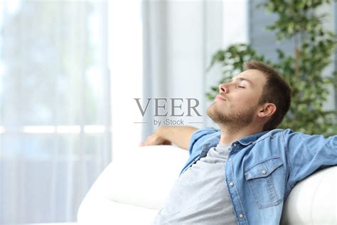 一个男人躺在家里的沙发上休息照片摄影图片_ID:133177296-Veer图库