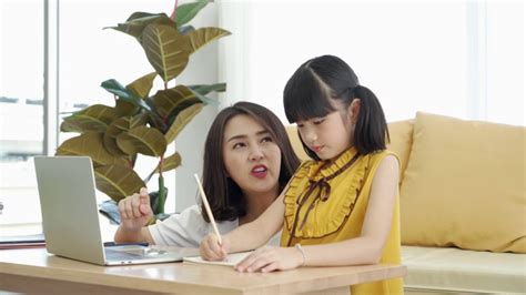 亚洲妈妈教孩子的女儿学习网上从家里，e -学习或自学家庭学校，倾斜向上的镜头视频素材_ID:VCG42N1278368633-VCG.COM