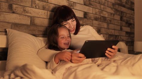 晚上，快乐的妈妈和学龄前的女儿在卧室里玩平板电脑视频素材_ID:VCG42N1387137939-VCG.COM