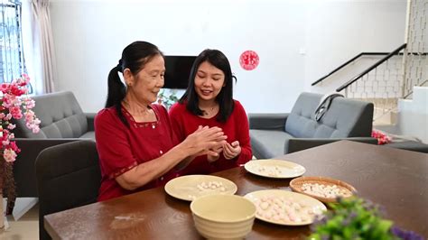一位亚洲奶奶和她的女儿和孙女在客厅里庆祝中国新年，并喝着橙汁视频素材_ID:VCG42N1353330781-VCG.COM