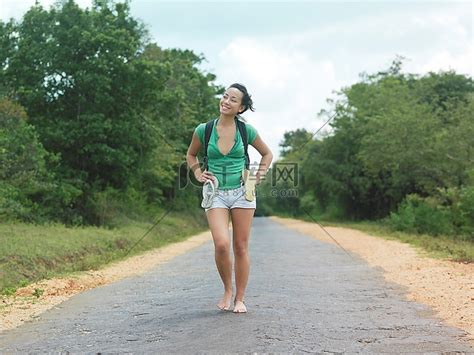 年轻女子赤脚走在乡间小路上微笑高清摄影大图-千库网