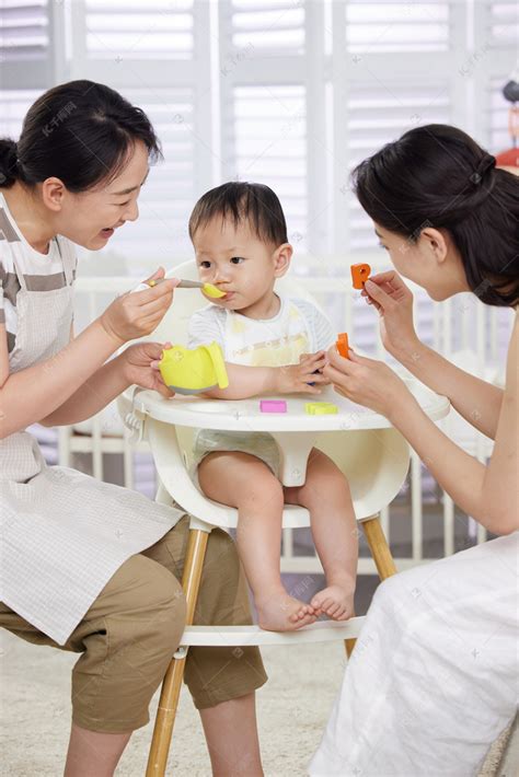 月嫂和年轻妈妈一起喂宝宝吃饭高清摄影大图-千库网